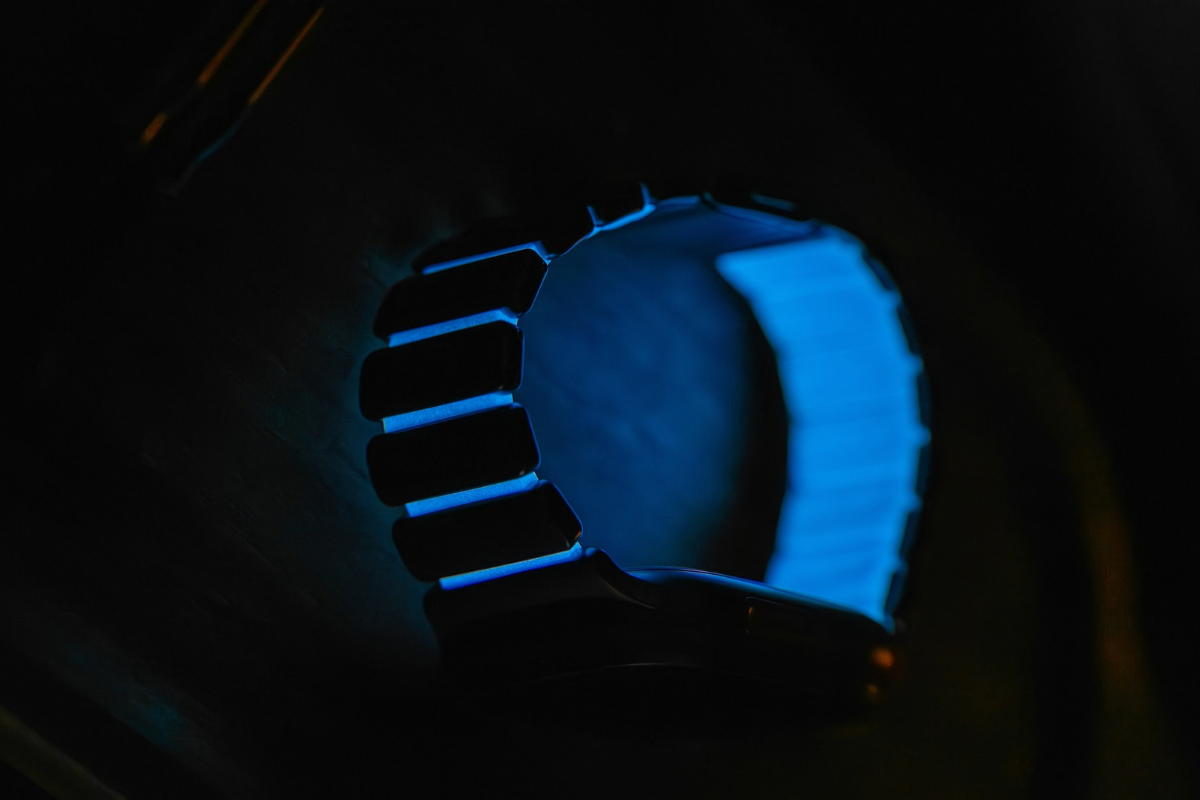 Світіння ремінця Nomad Stratos Icy Blue Glow у темряві: яскравий неоновий ефект фотолюмінесценції на зап'ясті.