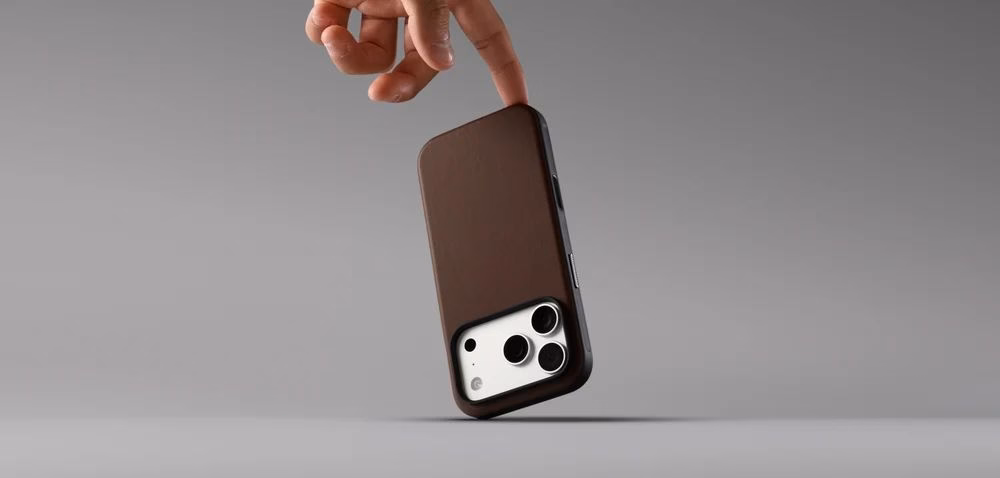 Людина тримає в руці смартфон у чохлі Nomad Modern Camino Brown