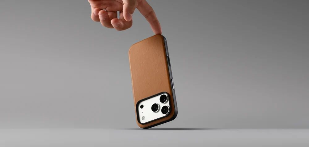 Людина тримає в руці смартфон у чохлі Nomad Modern Camino English Tan