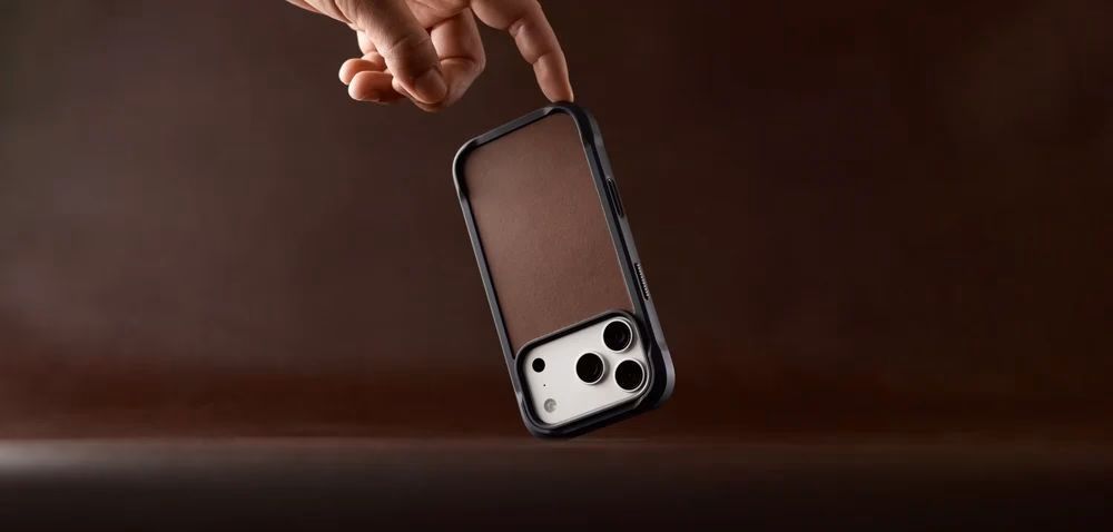 Шкіряний чохол Nomad Rugged Horween Rustic Brown у руці на коричневому фоні