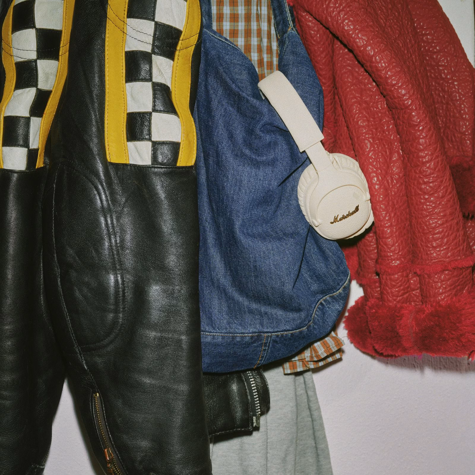 Наушники Marshall Monitor III ANC Cream подвешены на джинсовую сумку рядом с винтажной одеждой в стиле кэжуал.