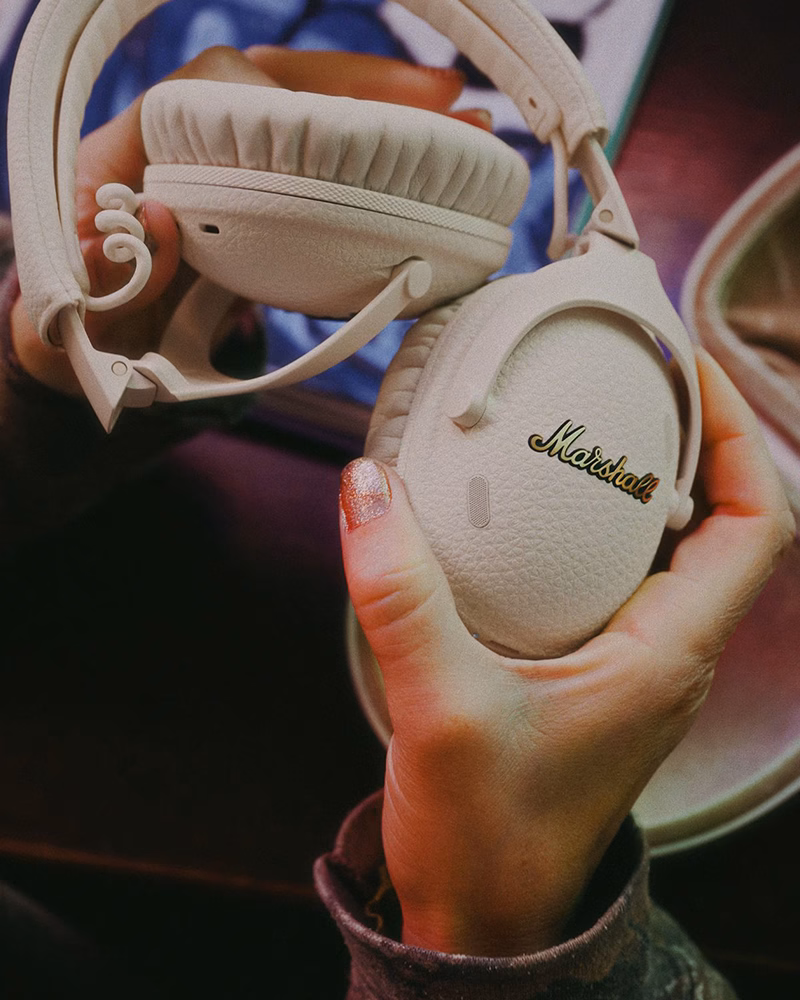 Пользователь держит наушники Marshall Monitor III ANC Cream, демонстрируя их компактность и премиальные материалы.