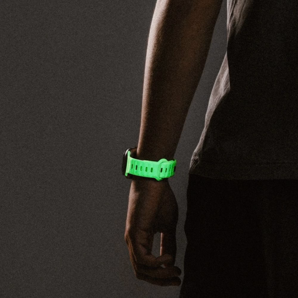 Мужская рука с Apple Watch Ultra на светящемся ремешке Nomad Glow 2.0, демонстрация спортивного дизайна и надежной застежки pin-and-tuck
