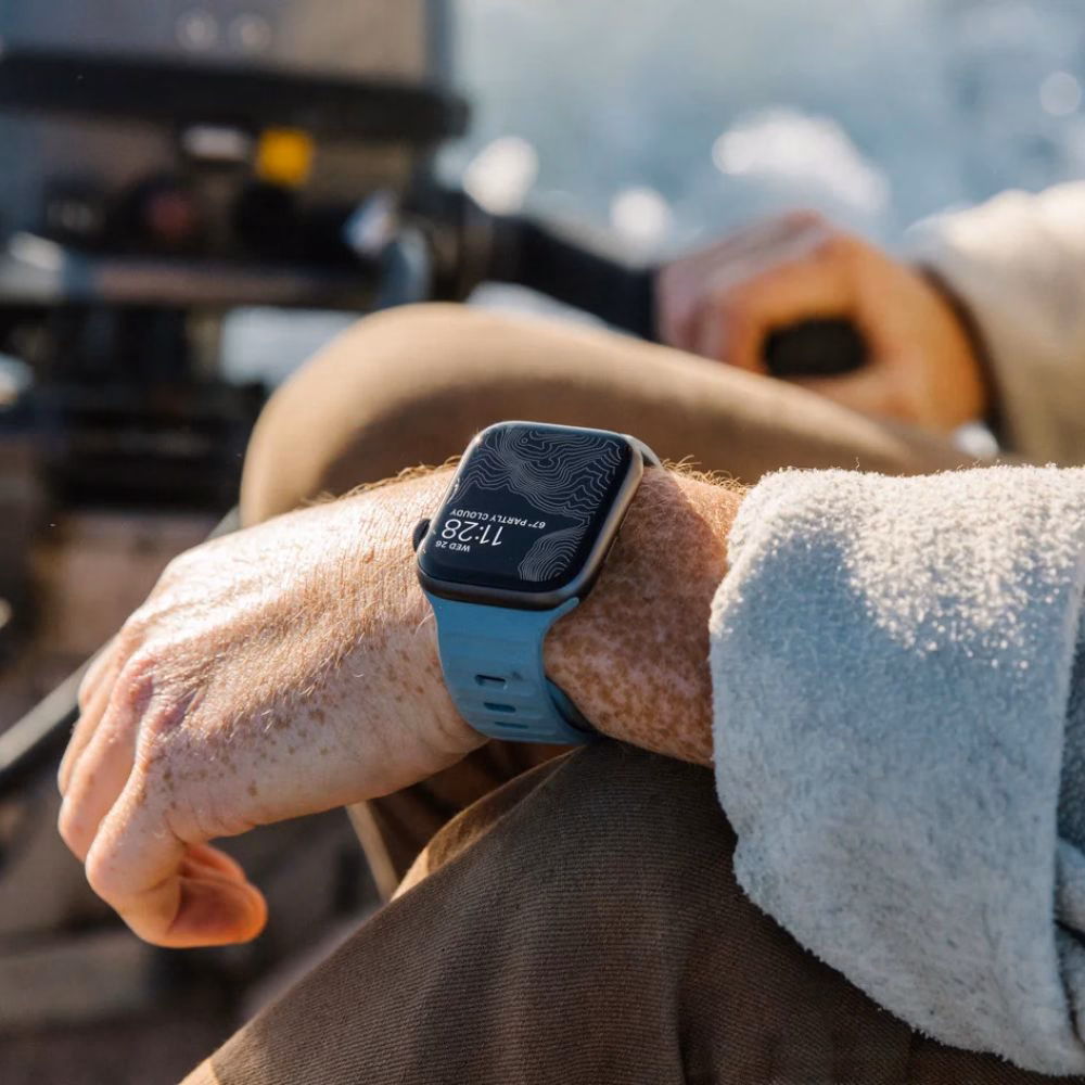 Мужчина в синем спортивном ремешке Nomad Sport Band Marine Blue на борту моторной лодки.