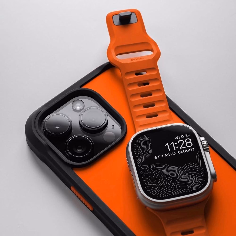 Силіконовий ремінець Nomad Sport Band Ultra Orange для Apple Watch Ultra на фоні iPhone у захисному чохлі Nomad Case