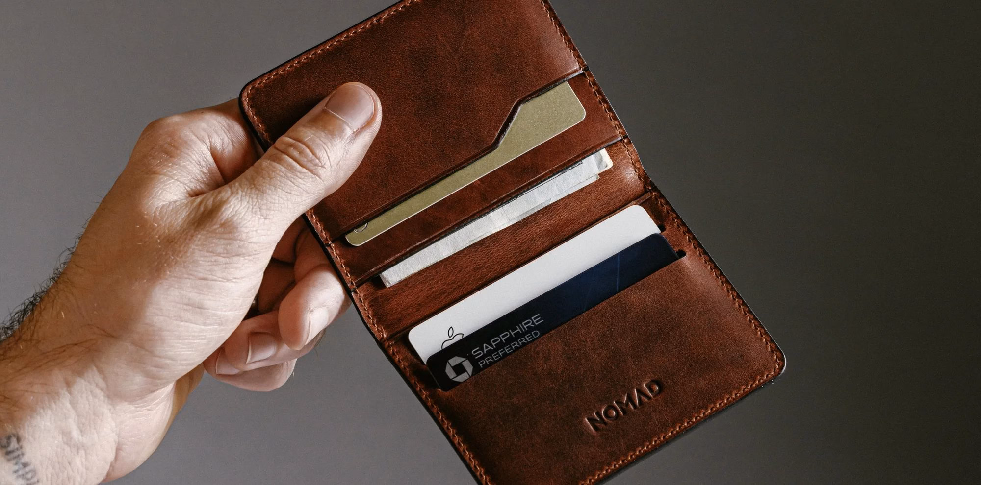 Гаманець Nomad Card Plus у руці в розгорнутому вигляді з картками