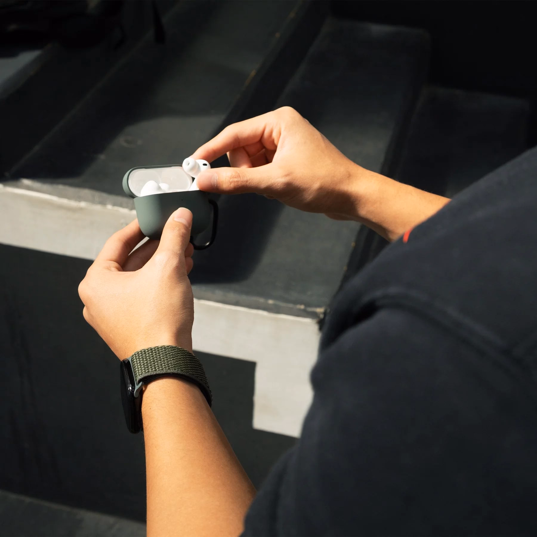 Мужская рука с ремешком Slate Green рядом с чехлом для AirPods