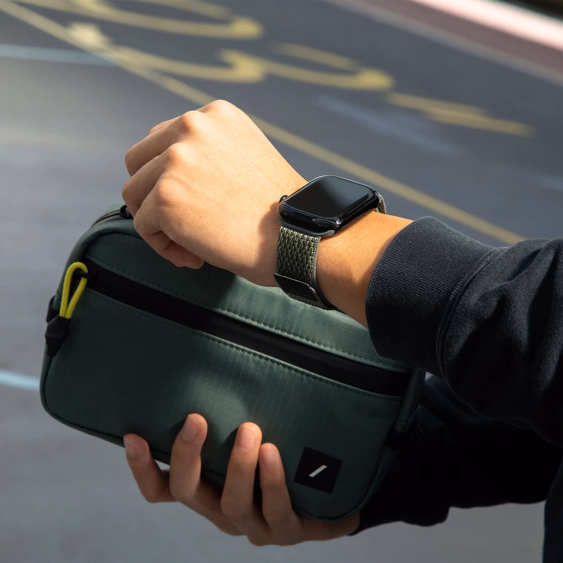 Ремешок Native Union Slate Green на руке рядом с сумкой-косметичкой