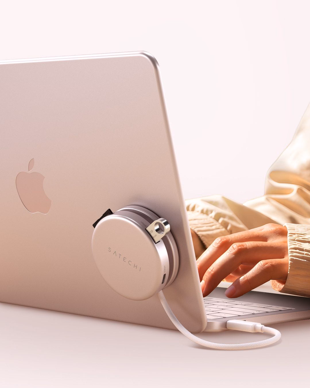 Дівчина працює за рожевим MacBook Neo з адаптером Satechi OntheGo