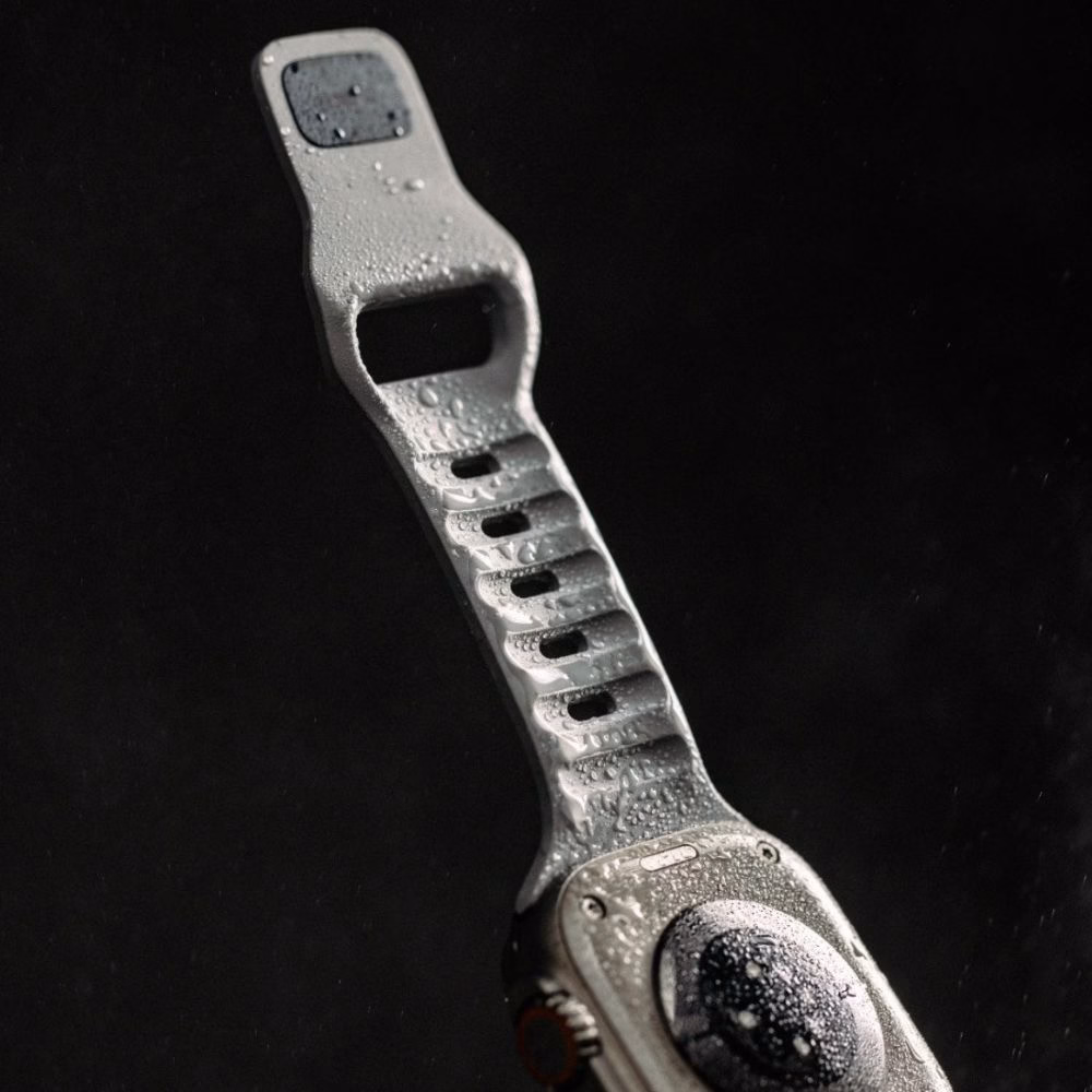 Водонепроникний силіконовий ремінець Nomad Sport Band для Apple Watch Ultra з краплями води на чорному фоні, демонстрація вологовідштовхувальних властивостей.