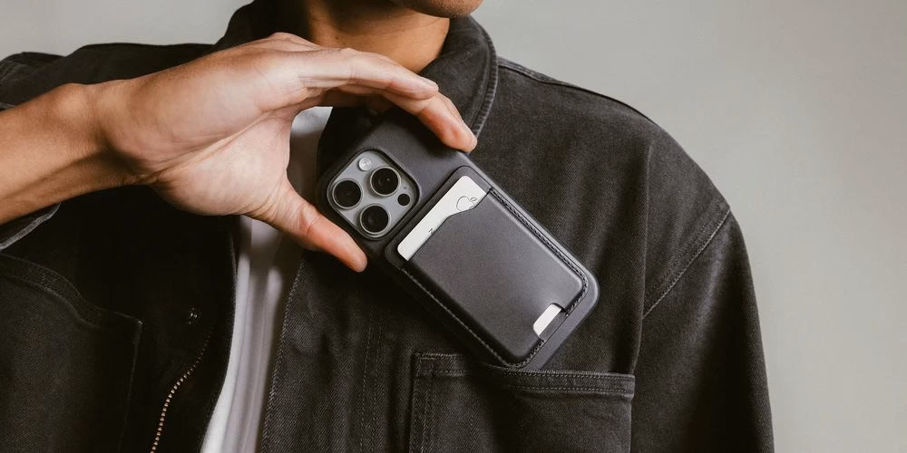 Мужчина достает iPhone с кошельком Nomad Leather Mag Wallet из кармана
