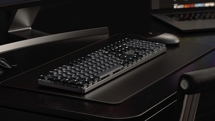 Вид механической клавиатуры Satechi SM3 Slim с подсветкой в темном интерьере на кожаном коврике рядом с мышкой.