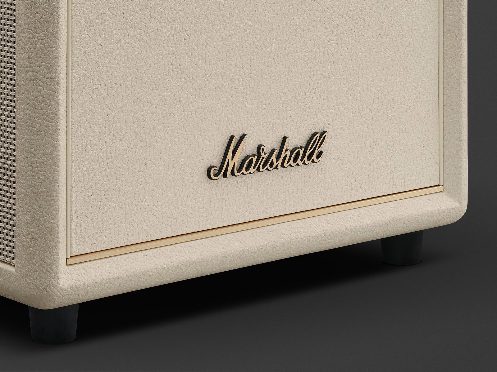 Крупний план логотипа Marshall на сабвуфері серії Heston у кремовому кольорі з фірмовою текстурою під шкіру та золотистою лінією